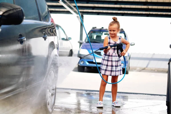Маленька дівчинка миє авто в автомийці — стокове фото