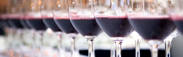 Szklanki czerwonego wina w wiersz w tabeli — Zdjęcie stockowe