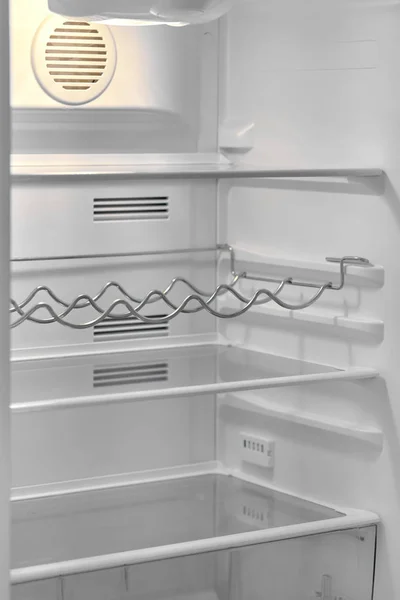 Open door of modern refrigerator with empty shelves