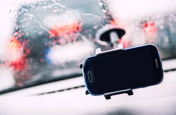 Smart phone on holder, rainy weather seen through wind shield — Stock Photo, Image