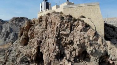 Drone aşağı görünüm Mesa Roldan Lighthouse kayalık dağın tepesinde yer alan, yoğun otoyol üzerinden üst köprü kurşun üzerine, Cabo de Gata-Nijar Natural Park, Almeria Eyaleti, Endülüs. İspanya