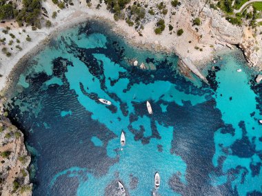 Palma de Mallorca Cala Blanca Andratx üzerinde parlak mavi koyda demirlemiş yatlar yukarıdan doğrudan bakış drone noktası, kayalık sahil nefes kesen görünümü, Balear Adaları İspanya