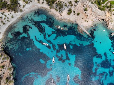 Drone point of view directly from above moored yachts on the bright blue bay on the Cala Blanca Andratx in the Palma de Mallorca, rocky coast breathtaking view, Balearic Islands Spain clipart