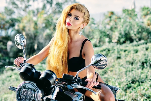 Sexig blond ung kvinna klädd i svarta underkläder sitter på motorcykel — Stockfoto