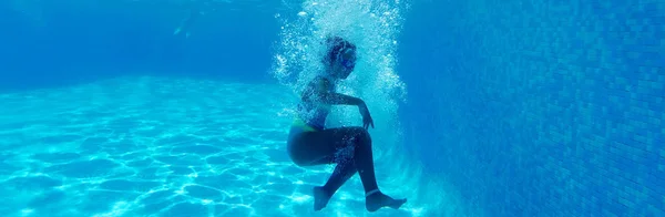 Fotografia subacquea orizzontale, momento di caduta bambina in acqua blu della piscina, bambino circondato da bolle, spazio copia freespace per testo pubblicitario, concetto di stile di vita sano attivo — Foto Stock