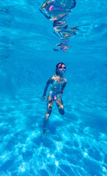 Fotografía submarina de inmersiones de niña al fondo de la piscina — Foto de Stock