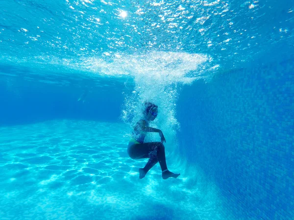 Petite fille entourée de bulles tombe dans l'eau bleue de la piscine — Photo