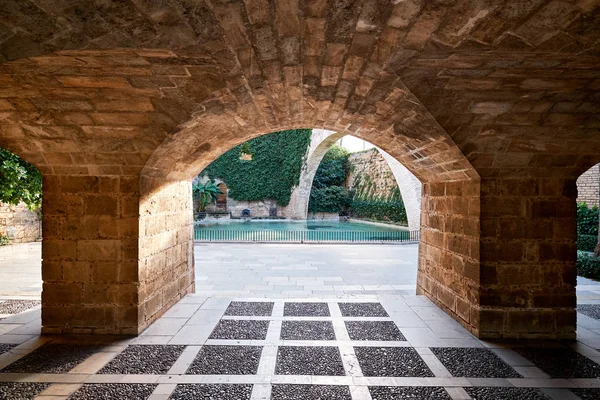 Внутренний двор с видом на бассейн через каменистую арку, Собор Ла Сеу , — стоковое фото