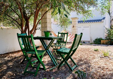 Yemyeşil ağacın altında masa ve sandalyeler ile Pretty iç bahçesinde