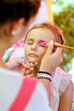 Sanatçı küçük sevimli kız bir yüzünde resim oluşturur