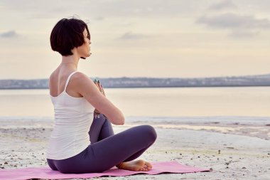Doğa üzerinde meditasyon lotus pozisyonda oturan yalnız kadın