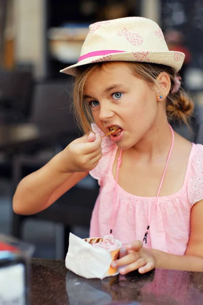 Beautiful little girl eating ice-cream sitting in outdoors cafe — Stock Photo, Image