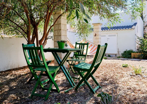 Schöner Innenhof mit Tisch und Stühlen unter sattgrünem Baum — Stockfoto