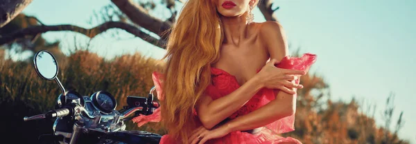 Gorgeous woman in red dress sitting on motorcycle horizontal view