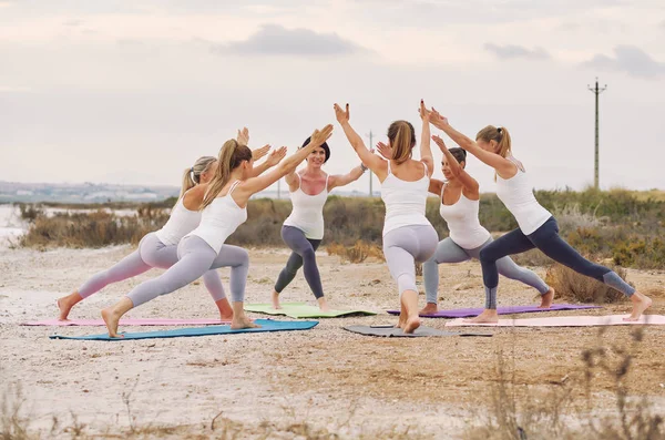 Skupina žen, které vykonávají cvičení Virabhadrasana Warrior — Stock fotografie