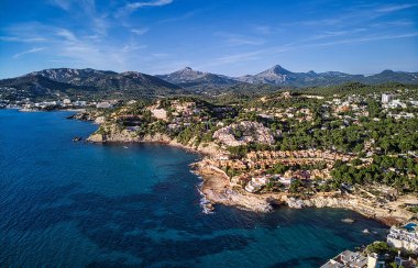 Costa de la Calma kıyı şeridinin hava manzarası ve Akdeniz 'in berrak yeşil suları. Çam ormanları arasındaki yamaçtaki villalar, vadideki sıradağlar. Mallorca, Mayorka, Balear İspanya