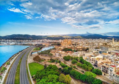 Hava aracı görüntüsü Majorca şehir manzarası, Akdeniz kıyısı boyunca uzanan yol ve Palma de Mallorca veya Le Seu 'nun ünlü Katedrali. Bulutlu karamsar gökyüzü, dağ vadisi. Balear Adaları. İspanya