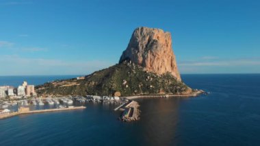 İnsansız hava aracı Penon de Ifach ya da Calpe 'nin Doğal Parkı tatil köyündeki Penyal d' Ifac d 'Ifac kireçtaşı uçurumuna bakıyor. Akdeniz, güneşli bir gün ve liman. Alicante ili, Costa Blanca, İspanya