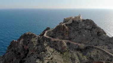 Cabo de Gata eski deniz feneri kayalık dağın tepesinde. Akdeniz 'de uçan kuş sürüsü tarafından çevrelenmiş insansız hava aracı görüş feneri. Almerya, İspanya