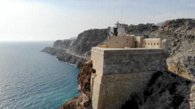 Cabo de Gata deniz feneri kayanın tepesinde. Akdeniz dağ yolu ile çevrili, kumtaşı kayalıkları manzarası boyunca uzanan insansız hava aracı görüntüsü. Almerya, İspanya