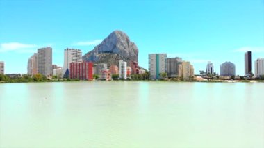 Calpe, İspanya - 3 Temmuz 2020: Calpe kentsel ufuk çizgisi, Penon de Ifach veya Penyal de Ifac kayası, flamingo kuşları sürüsü ile tuz gölü, mavi gökyüzü, güneşli bir gün, insansız hava aracı bakış açısı. Costa Blanca İspanya