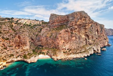 Aerial photo drone point of view picturesque Cala del Moraig in Benitachell coastal town. Bright turquoise waters bay of Mediterranean Sea white sandy beach, huge cliffs coastline. Costa Blanca. Spain clipart