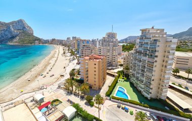 Şemsiyeli ve tatilcili kumsal, Penyal d 'Ifac Doğal Park manzaralı. Turkuaz mavi deniz suyu yaz günü. Calpe İspanyol tatil köyünün deniz kenarı. Costa Blanca, Alicante ili, İspanya