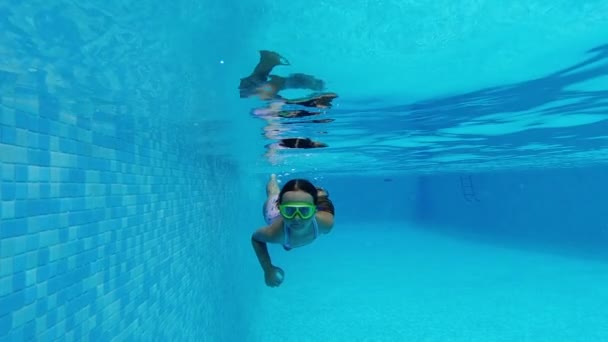 スローモーションビュー7 8歳の少女は水着を着用し 水中に沈んでゴーグルはプールで夏休みの水泳をお楽しみください アクティブなライフスタイルとスポーツ活動のコンセプト — ストック動画