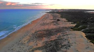Sandy Dunes plaj manzarası üstten. Drone 'un kıyı şeridi Akdeniz sörfü, pembe parlak, tüylü bulutlar mavi akşam gökyüzü. Alicante La Mata ili, Torrevieja, Costa Blanca, İspanya