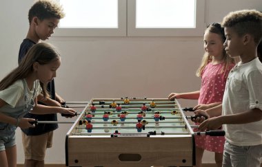 Çok kültürlü, sevimli çocuklar evde durup arkadaşlarıyla langırt oynuyorlar. Futbol aşığının masa üstü versiyonu. Alfa nesli çocuk konseptinin eğlenmesi ve yeniden yaratılması