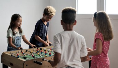 Çok kültürlü, sevimli çocuklar evde durup arkadaşlarıyla langırt oynuyorlar. Futbol aşığının masa üstü versiyonu. Alfa nesli çocuk konseptinin eğlenmesi ve yeniden yaratılması