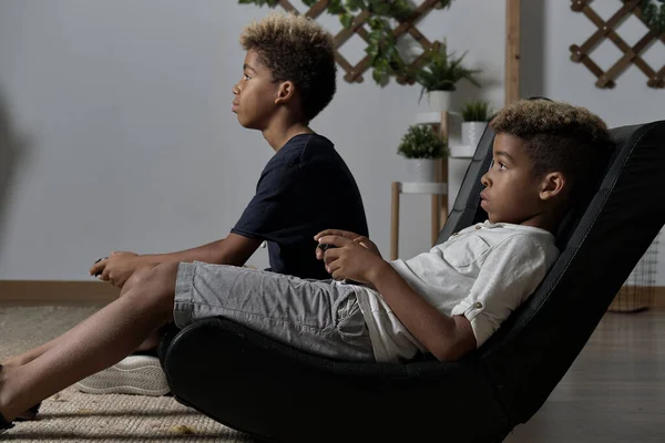 两个混血的兄弟一起坐在室内打台球 阿尔法世代的后代沉迷于虚拟游戏问题的概念 — 图库照片