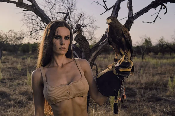 Beautiful woman posing on nature with eagle