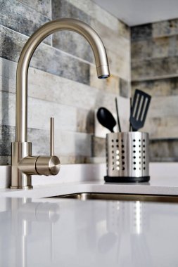 Modern iç mutfağın arka planında musluk ve lavabo var.