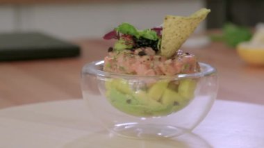 Dönüş tabağında, avokado, siyah havyar, salata ve cips yapraklarıyla süslenmiş somon katranının porsiyonunu servis ederken yavaş çekim görüntüsünü kapat. Restoran menüsü yemek konsepti