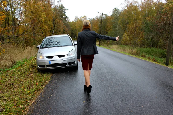 El día de otoño el coche se rompió y la chica en un vestido con un sombrero coge otro coche para ayudar — Foto de Stock