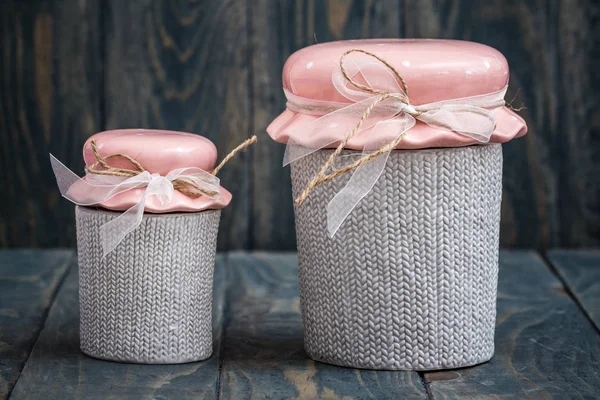 Gray and pink cute decorative ceramic jars on blue wooden background