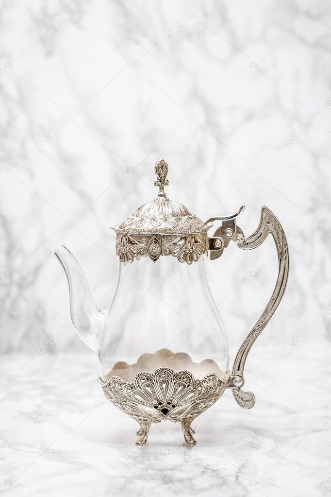 Decorative glass and metal jug on white marble