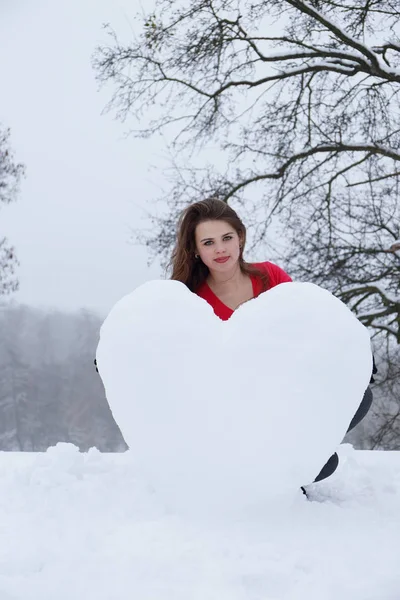Mulher molda um coração da neve — Fotografia de Stock