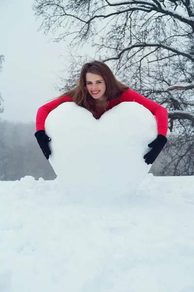 Mulher abraçando o coração da neve — Fotografia de Stock