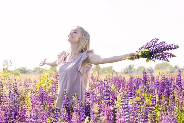 フィールド上のルピナスの花束と自由で幸福な女性 — ストック写真