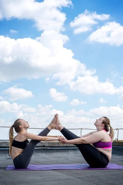 Duas meninas treino asana barco ioga pose — Fotografia de Stock