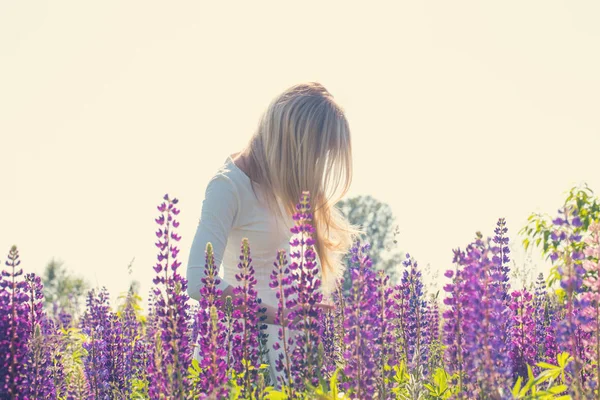 Blond flicka på fältet med lupiner — Stockfoto