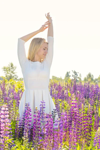 Vacker flicka dansar på fältet med lupiner — Stockfoto