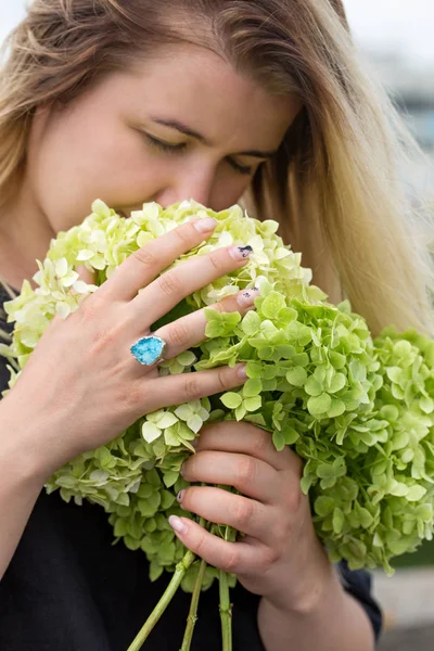 Mladá žena čichání kytice z hortenzií — Stock fotografie