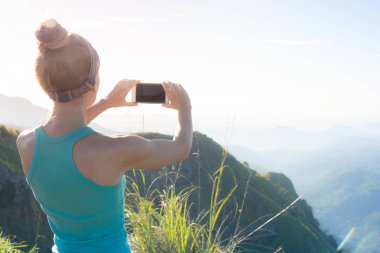 Bir kız güneşin doğuşunu dağlarda çekiyor