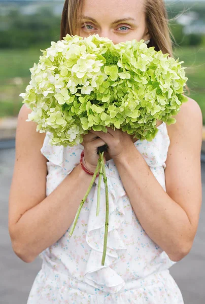 Junge Frau schnuppert an einem Hortensienstrauß — Stockfoto