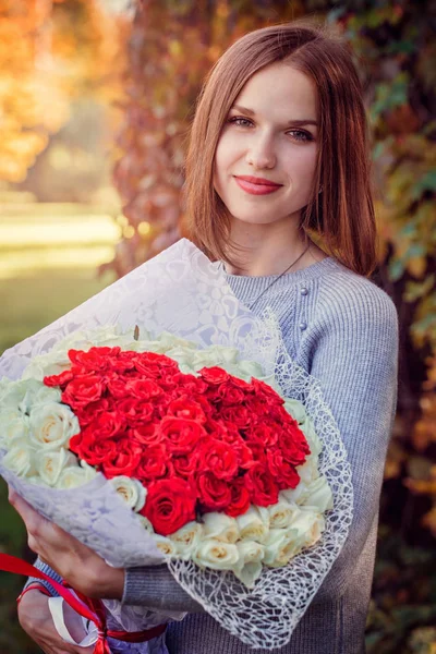 Žena s kyticí růží na podzim park — Stock fotografie