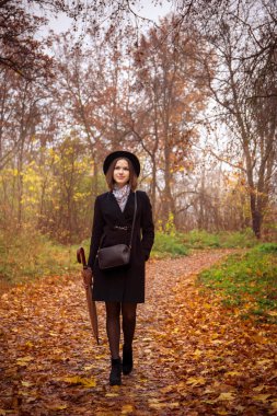 Genç bir kadın sonbahar parkta yürüyor