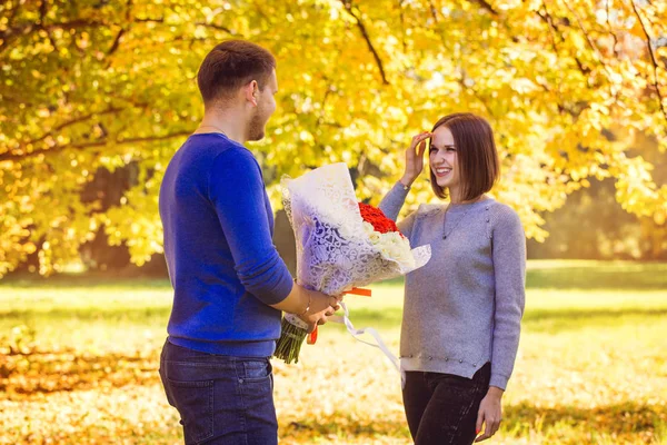A young man gives a bouquet to his woman — Stock Photo, Image